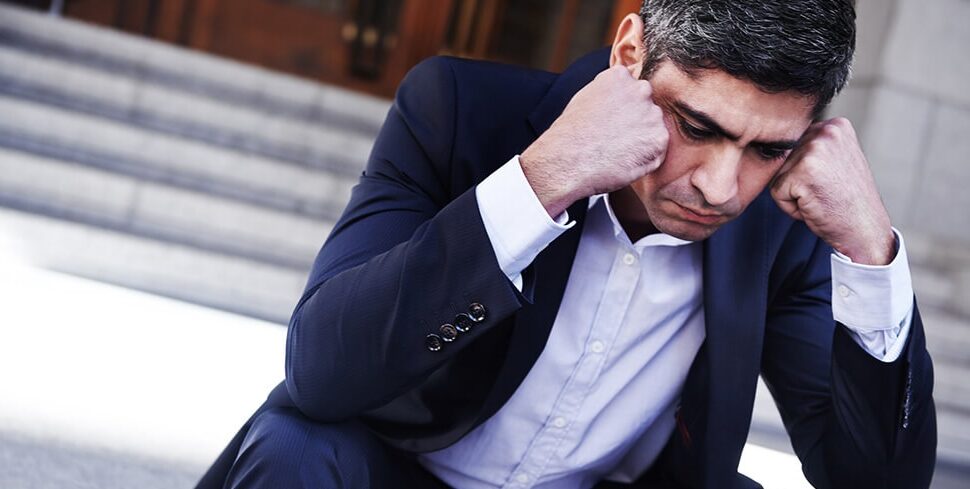 Stressed business professional sitting with head in hands, representing workplace issues that may lead to constructive dismissal claims
